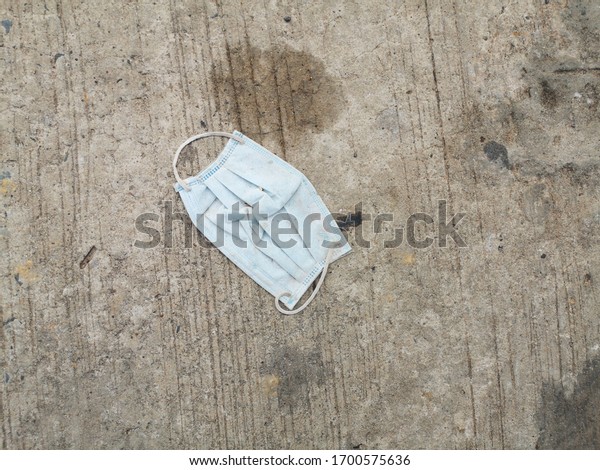 Dirty hygienic medical\
mask on ground.