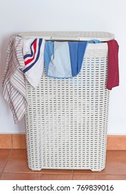 A Dirty Laundry Hamper With Some Clothes Coming Out From The Cover.