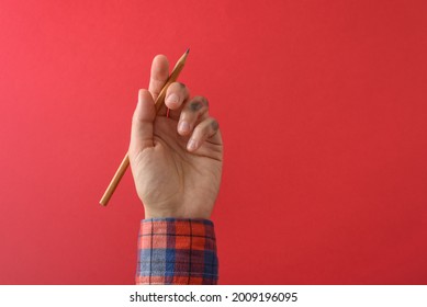 La sucia mano izquierda en la camisa roja después de escribir. Concepto del día de la izquierda.