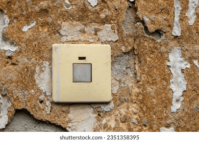 a dirty light switch on a damaged house wall