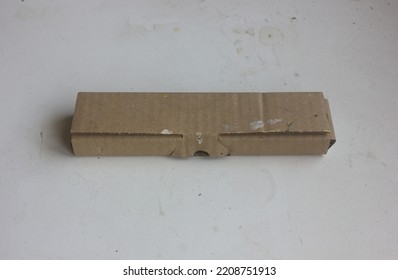 The Dirty Long Thin Brown Recycled Carton Box Is Isolated On A Textured Background, For Stationery Parcel Mockup Or Eco Packaging Design Presentation.