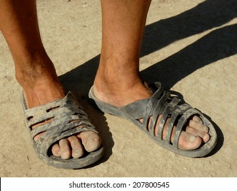 Dirty Male Feet In Rubber Slippers On Dried Earth