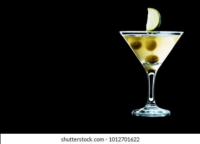Dirty martini served with green olives and a slice of lime. A glass with cocktail isolated on a black background. Place for your text.