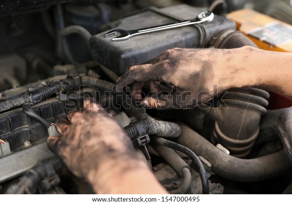 Dirty mechanic\
fixing car, closeup of\
hands
