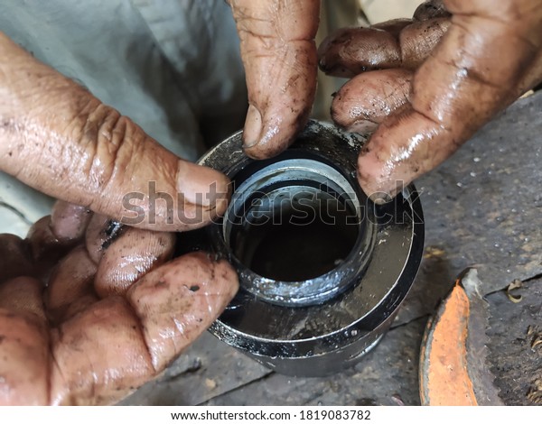Dirty\
mechanic\'s hands work on a small metalwork\
piece
