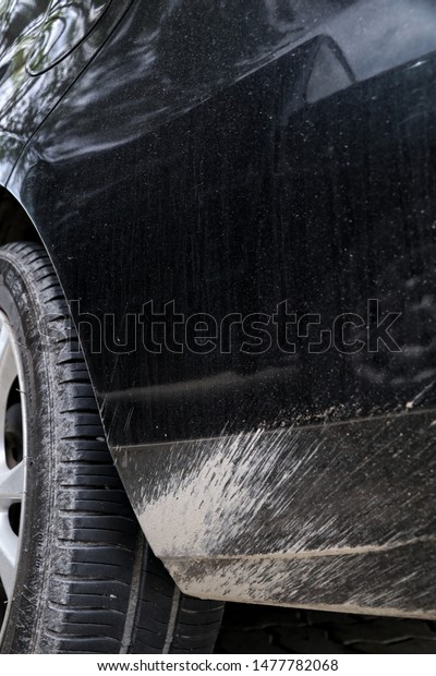 Dirty mud stains on surface of the black car.\
Car care concept.