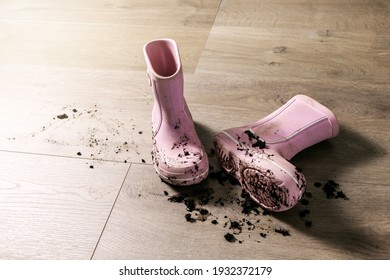 dirty muddy kids rubber rain boots on laminate floor