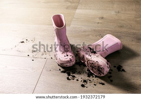 dirty muddy kids rubber rain boots on laminate floor