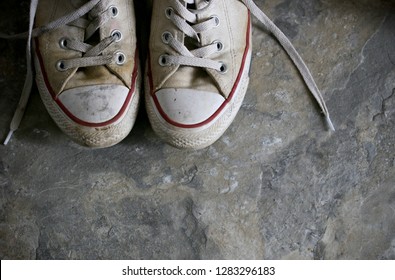 Dirty Muddy Tennis Shoes On Stone Floor In Upper Left Of Image Room For Text.