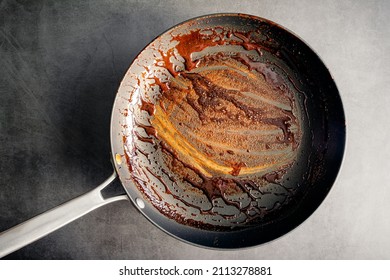 Dirty Nonstick Skillet Used to Make a Balsamic Reduction: An unwashed frying pan covered in a sticky glaze - Shutterstock ID 2113278881