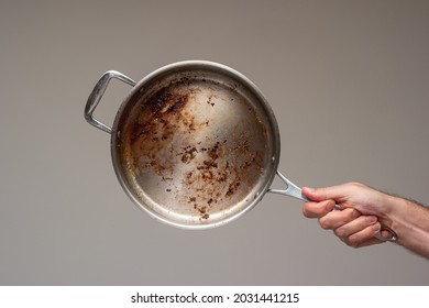 Dirty Oily Burnt Metal Frying Pan Held In Hand By Male Hand. .