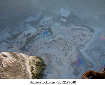 Dirty oily film on the surface of the turquoise sea on the beach. industrial dump waste water spill.
Oil film pollution. Colorful oil film on water. industrial dump waste water spill.