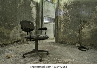 A Dirty And Old Office Chair, Standing In A Room Of An Abandoned Psychiatric Hospital, With Dirty Floor And Old Walls, Creating A Scary Scene  