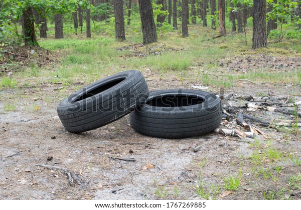 Dirty old rubber tires in\
forest