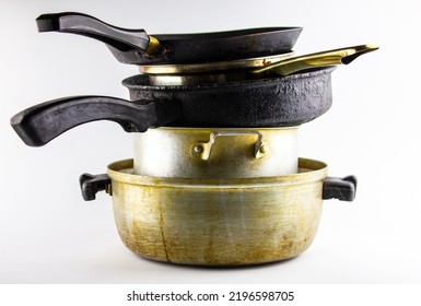 The dirty old utensils in a stack of metal on a white background, isolated. Dirty pots, frying pans for cooking.