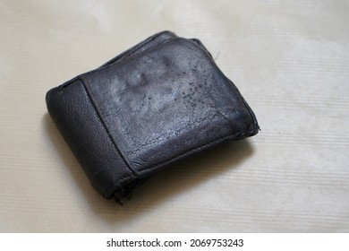 
Dirty And Old Wallet On White And Brown Background. 