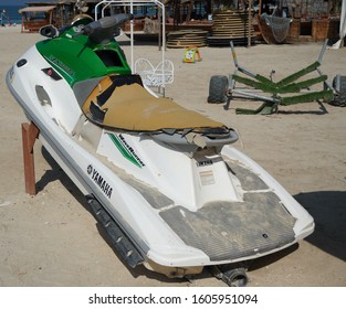 Dirty Old Yamaha Jet Ski Parked On The Beach Of Holiday Season. Old Jet Skis On The Beach On Wooden Trailer. Green And White Jet Ski - Dubai Uae January 2020