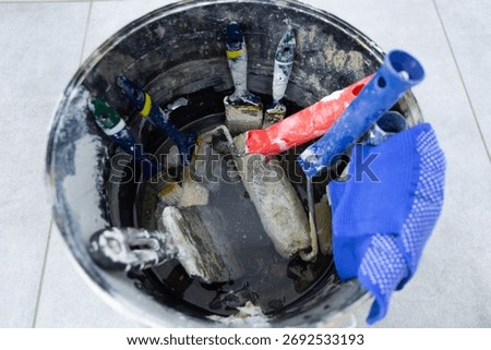 Dirty painter's tools after work in a bucket of solvent.