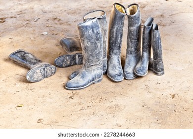 dirty plastic riding boots standing at the muddy gry ground - Powered by Shutterstock