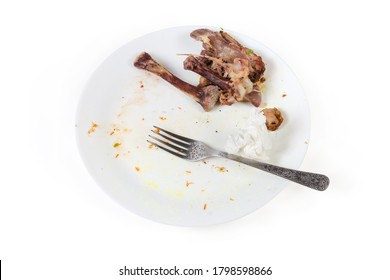 Dirty Plate After Eating With Gnawed Chicken Leg Bones, Used Paper Napkin And Fork On A White Background
