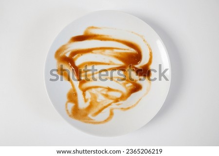 Dirty plate isolated, empty bowl after dinner, ready lunch, smeared ketchup sauce on white plate background, top view