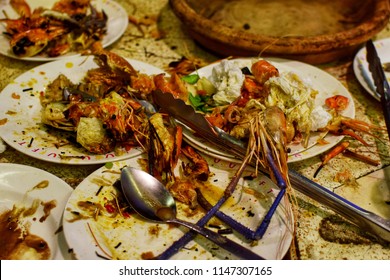 Dirty Plates With Food Scraps In The Buffet Restaurant. Close Up Of Dirty Dishes And Seafood Waste After Eating.