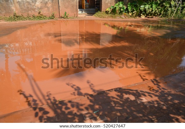 Dirty pool with the red earth on the road to the\
pits in India