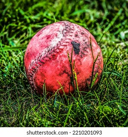 Dirty Red Ball Lying On The Green Grass In The Backyard.