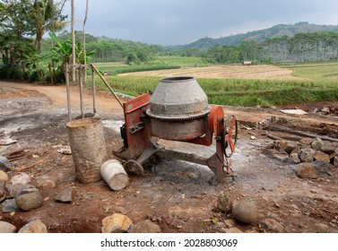 The Dirty Red Cement Mixer Is On The Side Of The Road Near The Rice Fields.