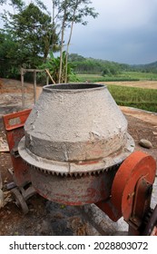 The Dirty Red Cement Mixer Is On The Side Of The Road Near The Rice Fields.