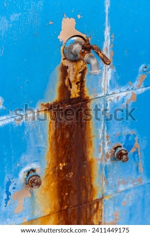dirty rusty faucet on blue tiles