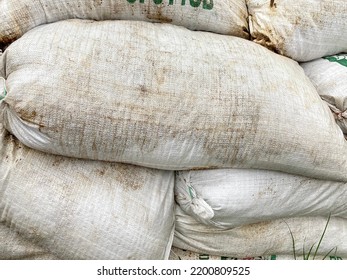 Dirty sacks filled with soil arranged on the roadside. The sack is an old animal feed sack.