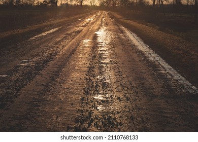 Dirty Sand And Gravel Road With Puddles In Sunset Golden Light