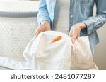 Dirty sauce stain cloth, housewife asian young woman holding white shirt, showing making cloth stain, spot dirty or smudge on clothes for cleaning before washing, maid female working at home concept.