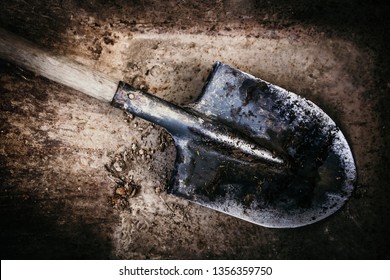 Dirty shovel in fresh soil. Deep hole in the ground. Rusty old tool on construction. Dig deep ditches and pits.
