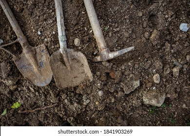 Dirty Shovel, Pickaxe And Spade Lying On The Ground. Tools For Seasonal Garden Work And For Digging At Construction Site.