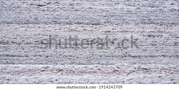Dirty\
snow slush, salt and melting reagents on the road with traces from\
cars. Snow and slush covered highway after huge snowfall, dangerous\
driving conditions. Road under the snow,\
slippery