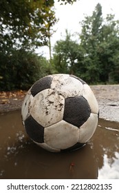 Dirty Soccer Ball In Muddy Puddle Outdoors