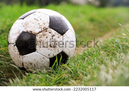 Dirty soccer ball on green grass outdoors, closeup. Space for text