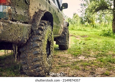 Dirty SUV is standing on the lawn after an off-road race, covered in slush. A beautiful photo of nature and a offroader in a beautiful meadow