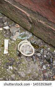 A dirty used rubber condom, surrounded by broken glass and cigarette butts, discarded in a dirty city alleyway. Safe sex prostitution sexual health. sexual disease prevention. 