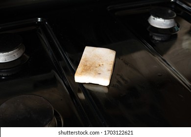 A Dirty, Used White Eraser Sponge On Top Of A Stovetop. Concept: Cleaning.