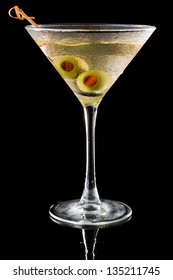 dirty vodka martini served on a dark bar garnished with large green olives