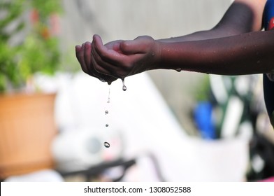 Dirty Water Dripping From Hands Of An African American Child