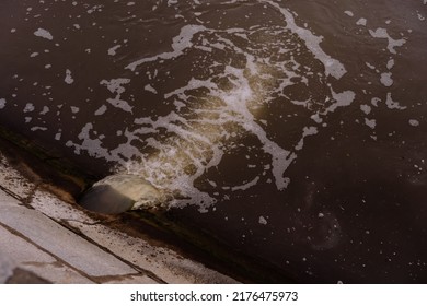 Dirty Water Flowing Into The River In The City.