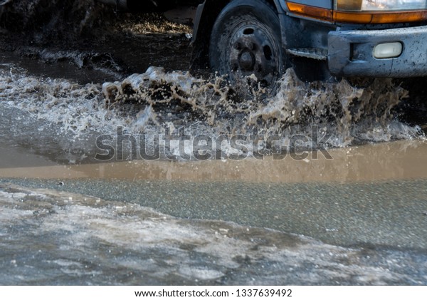 dirty wave of spray\
from under the wheels of a truck. Water on the road. Spray from\
under the wheels of cars.