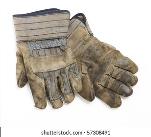 A dirty and well-worn pair of canvas and leather work gloves on white background.