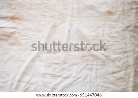 Dirty white bedding sheet ,Body oil stains odors stains and other dirt ,Top view of unmade bedding sheets or white fabric wrinkle texture background,