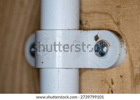 dirty white plastic pipe wall clamp bracket  and pipe super close-up with shallow depth of field