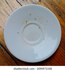 A Dirty White Plate, Placed On A Wooden Table